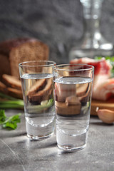 Cold Russian vodka with snacks on grey table, closeup