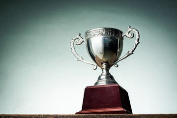 Old trophy on old wooden table with vintage tone light shading background - obrazy, fototapety, plakaty