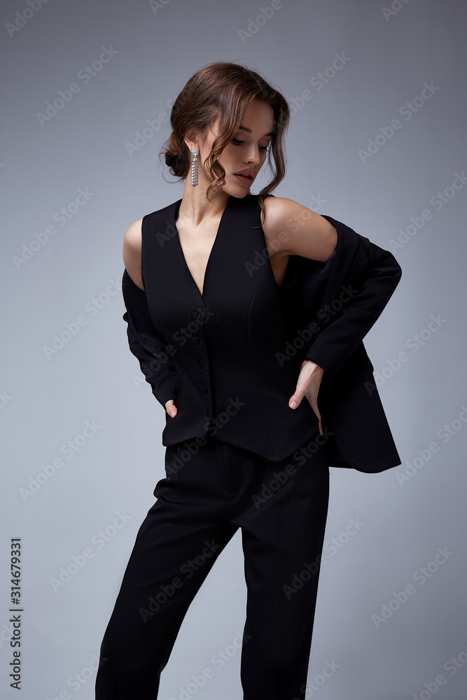 Wall mural Sexy beautiful woman fashion glamour model brunette hair makeup wear black suit trousers jacket clothes office dress code casual party style accessory date walk girl skinny body shape studio.