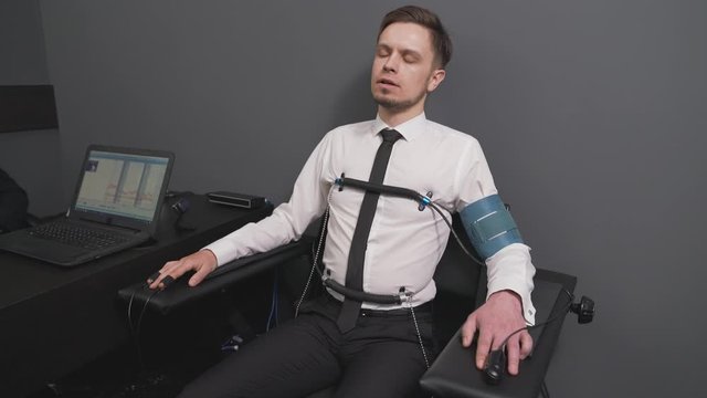Young man in sensors checking with computer polygraph