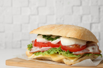 Delicious sandwich with fresh vegetables and mozzarella on white table