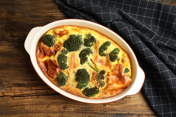 Tasty broccoli casserole in baking dish on wooden table, top view