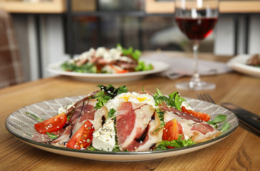 Delicious prosciutto salad with vegetables served on wooden table indoors. Space for text