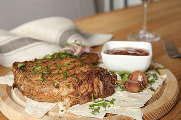 Delicious grilled pork chop on wooden board, closeup