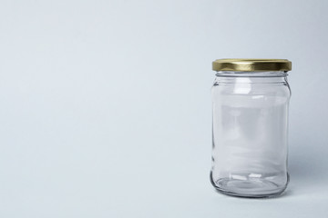 Closed empty glass jar on light background, space for text