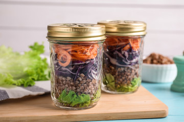 Glass jars with healthy meal on light blue wooden table