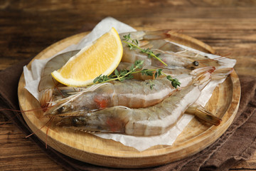 Fresh raw shrimps with lemon slice on wooden table
