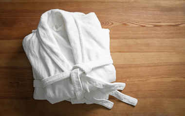 Clean folded bathrobes on wooden background, top view