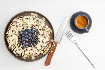 Homemade chocolate cheesecake with blueberries and almond slices on white wooden table. Top view.