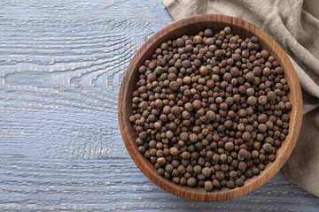 Bowl with peppercorns on wooden table, flat lay