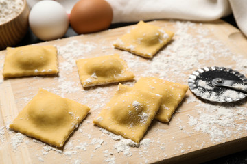 Fototapeta na wymiar Raw ravioli on wooden board, closeup view. Italian pasta