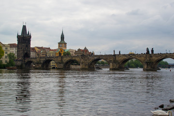 Fototapeta na wymiar Vltava river flowing through Prague with Charles Bridge (Karlův most) and Old Town Bridge Tower (Staroměstská mostecká věž) at the background (Czech Republic)