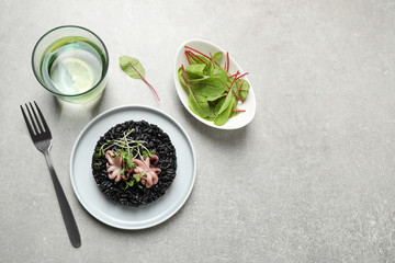 Delicious black risotto with seafood served on light grey table. Space for text