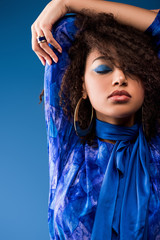 stylish african american woman in dress with closed eyes isolated on blue