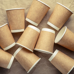 Paper cups for coffee on a light crumpled paper background.