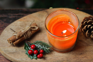 Beautiful Christmas orange mandarin candle on a wooden stand with sticks of whole cinnamon, sprig of mistletoe and a Christmas tree decorated with toys. Christmas New year evening mood, greeting card