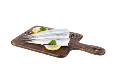 Packshot. Herring fillet on a wooden board, decorated with lemon, parsley and spices.