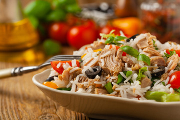 Italian tuna salad with rice, olives and capers. Front view. Natural wooden background.