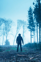 Man in black jacket with gun in foggy winter forest.