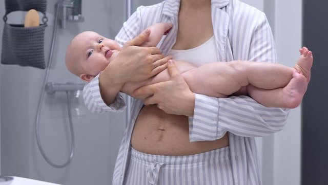 Young Mother With Postpartum Belly Holding Her Baby.