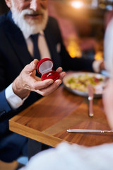 Will you marry me. Senior marriage proposal Senior man happily looks woman waiting answer marriage proposing. Elegant male in suit smile holding ring, woman hold white rose