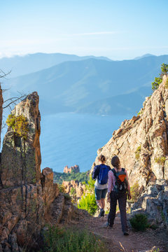 France. Corse. Corsica. Deux randonneurses &agrave; Piana sur uun sentier escarp&eacute; au milieu de rochers. En arri&egrave;re plan la mer m&eacute;diterrann&eacute;e.  Two hikers in Piana on a steep path in the middle of rocks.