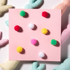 Conceptual Easter card, with multicolored fluffy rabbit tails on a pink paper background