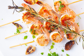 grilled shrimp on skewers. Grilled seafood on skewers with spices, herbs and lemon. delicious prawn. White plate. White background
