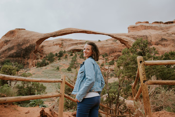 Fototapeta na wymiar Femme souriante devant la plus arche naturelle du monde à Arches National Park