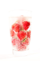 Water on fresh strawberry with dancing bubbles in tall glass isolated on white background. 