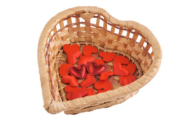 Small hearts in a wicker heart-shaped basket isolated on white.