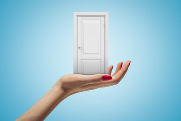Female hand holding white doorway on blue background