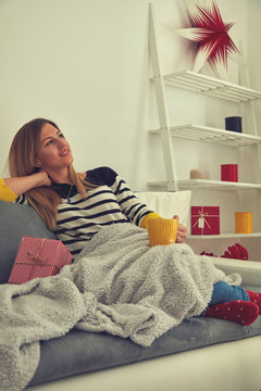 Woman sitting on sofa and drinking coffee/tea. Holiday concept.
