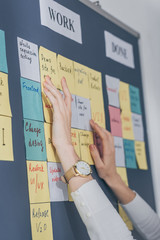 cropped view of scrum master touching sticky notes with letters in office