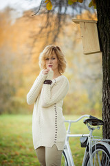 Beautiful autumn woman in a park with a bicycle. Posing tenderness romance. Autumn leaf fall yellow background