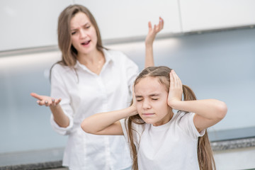 Mother scolds her daughter. Girl covers her ears and closed eyes. Family relationships