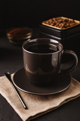 A black coffee Cup, metal jar of roasted coffee beans on a dark concrete table