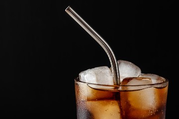Glass glass with soda and ice ,metal reusable straw for cocktails,close up,black background