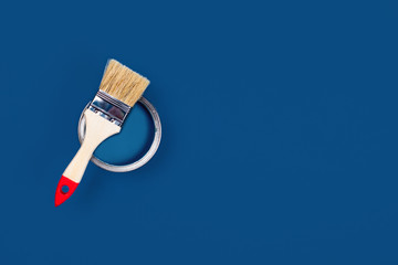 Renovation picture. Classic blue background with blue paint can and brush located on it. Flat lay,...