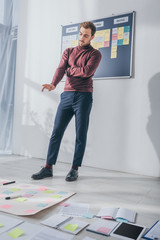 selective focus of pensive businessman gesturing while looking at sticky notes on floor