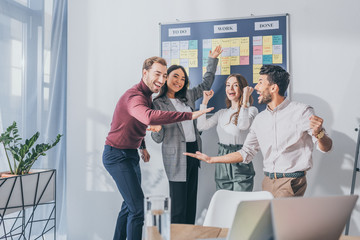 excited multicultural businesswoman and businessman celebrating in office