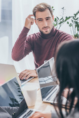 selective focus of handsome businessman thinking near laptops