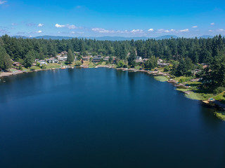 Tranquil Shady Lake on a bright clear day in summertime with trees reflecting in the water a blue sky and white clouds with lily pads dockside in Renton King County Washington State