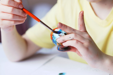Child painting eggs with paints on Easter holiday