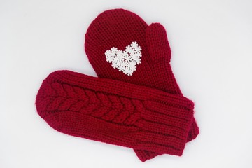 A knitted red mitten with white snowflakes in the shape of a heart on a white background, isolated. Сoncept of Christmas, winter, love, care and Valentine's day. Copy space