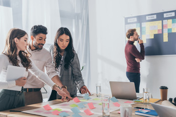 multicultural businesswomen and businessman pointing with fingers at sticky notes