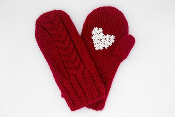 A knitted red mitten with white snowflakes in the shape of a heart on a white background, isolated. Сoncept of Christmas, winter, love, care and Valentine's day. Copy space