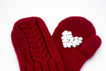 Close up of a knitted red mitten with white snowflakes in the shape of a heart on a white background, isolated. Сoncept of Christmas, winter, love, care and Valentine's day