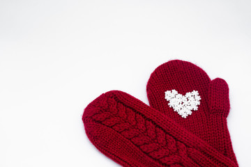 A knitted red mitten with white snowflakes in the shape of a heart on a white background, isolated. Сoncept of Christmas, winter, love, care and Valentine's day. Copy space