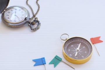 Compass, vintage hanging necklace watch and flag pin on white background, direction concept